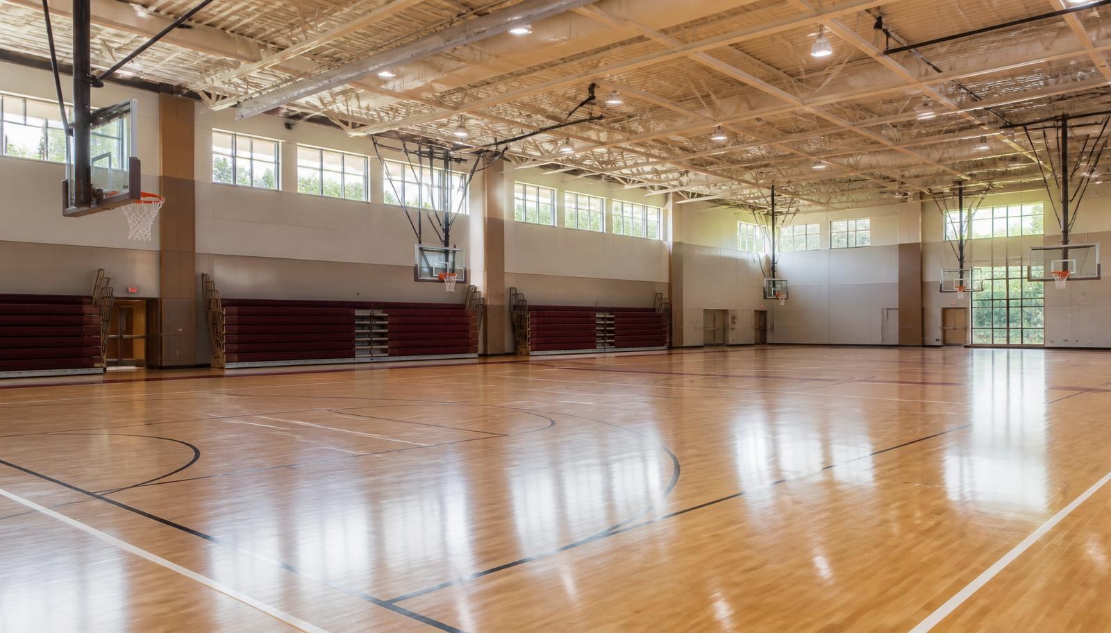 Interior of a community gym with several full basketball courts, hardwood floors and hoops
